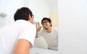 man brushing his teeth in the mirrot