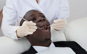 man sitting in a dental chair getting his teeth worked on